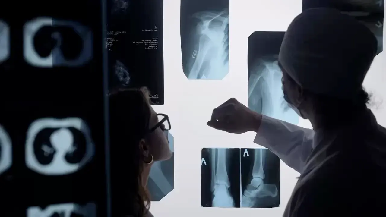 Two clinicians reviewing X-ray and CT images on a lightbox